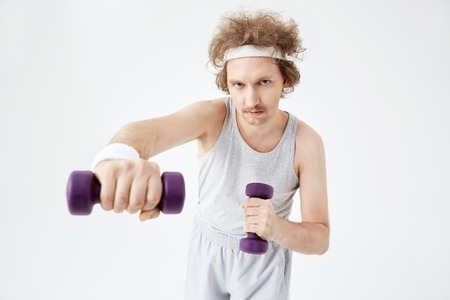 Young man working on arm muscles training with  dumbbellsの写真素材