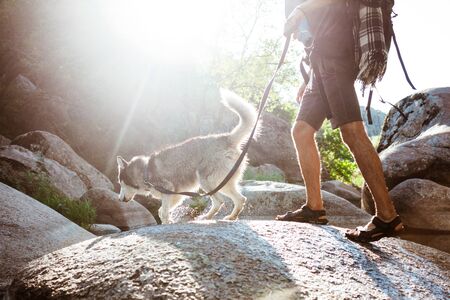 Young handsome man walking with huskies dog in canyon near water.の写真素材
