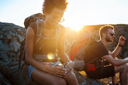 Young friends sitting on rock in canyon, looking at compass.の写真素材
