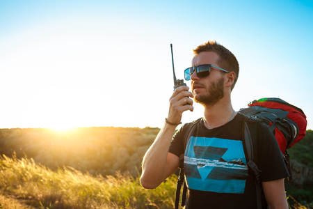 Young handsome man talking on walkie talkie radio, enjoying canyon view.の写真素材