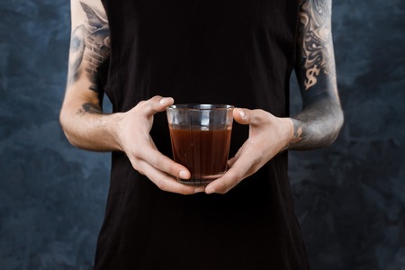 Male barista holding glass with coffee over grey background.の写真素材