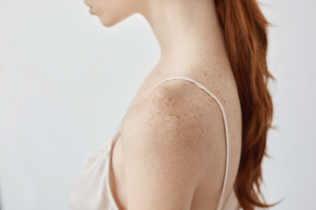 Close up portrait of tender young redhead freckled girl in lingerie over white wall.の写真素材