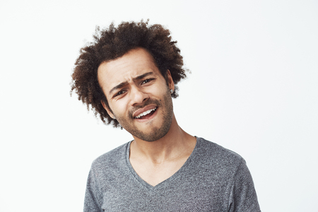 Upset displeased african man looking at camera over white background.の写真素材