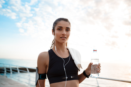 Portrait of young beautiful sportive girl at sunrise over seaside.の写真素材