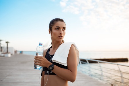 Portrait of young beautiful sportive girl at sunrise over seaside.