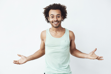 Cheerful african man smiling gesturing looking at camera over white background.の写真素材