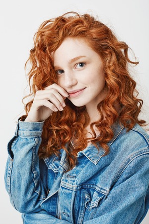 Portrait of cute young girl with red curly hair and freckles smiling looking at camera.の写真素材