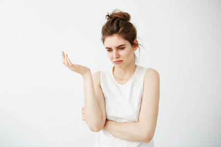 Displeased young beautiful girl with bun gesturing over white background.の写真素材