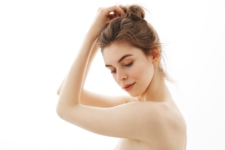 Portrait of young beautiful tender naked girl with bun posing in profile over white background.の写真素材