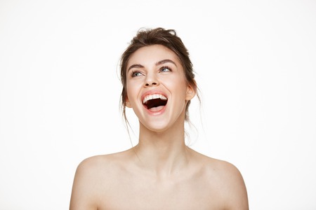 Cheerful beautiful naked girl rejoicing smiling laughing over white background. Facial treatment. Beauty and health.の写真素材