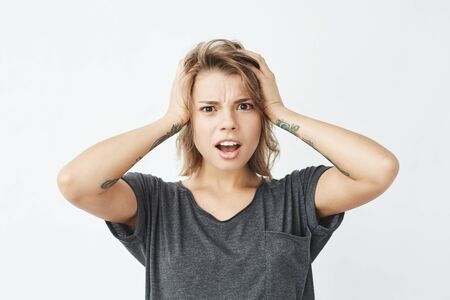 Displeased young pretty girl looking at camera ashamed holding head over white background.の写真素材