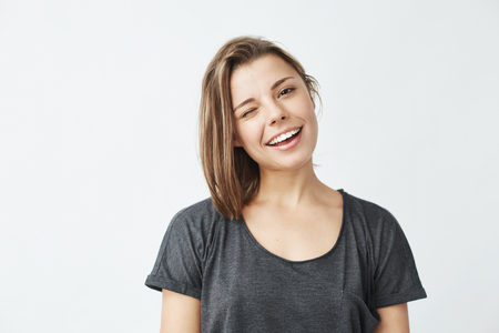 Cheerful young beautiful girl smiling winking looking at camera over white background.の写真素材