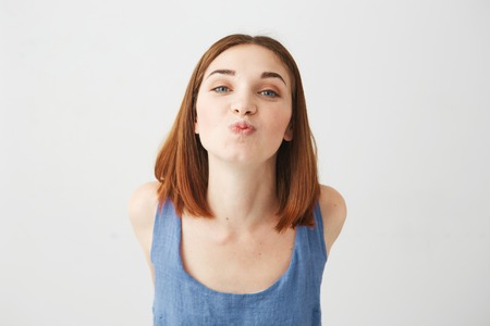 Portrait of cheerful young beautiful pretty girl looking at camera sending kiss over white background.の写真素材