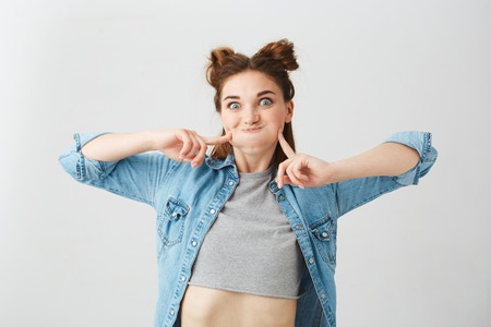 Portrait of funny young pretty girl with two buns making funny face fooling over white background.の写真素材