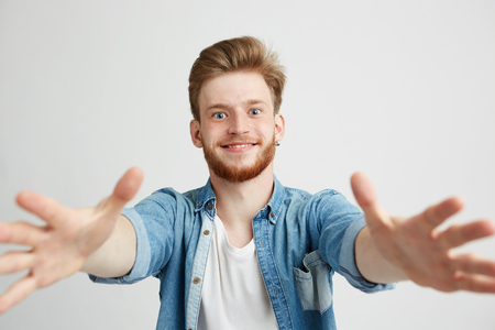 Portrait of young handsome man smiling looking stretching hands to camera over white background.の写真素材