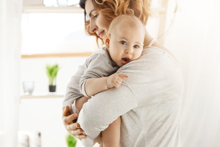 Young beautiful mother holds her little newborn son and calming him after bad dream. Sweet scene of...