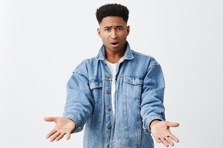 What the heck, man. Close up of young unhappy grumpy black-skinned american man in denim jacket with...
