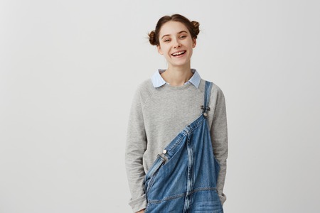Cheerful woman being in good mood laughing looking on camera over white wall. Happy emotions of carefree female smiling with teeth being contented. Positive human facial expressionsの写真素材