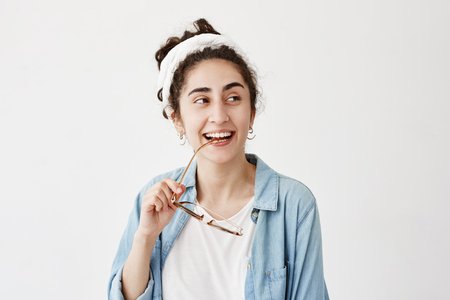 Happy smiling dark-haired female in do-rag in denim shirt, with sunglasses, has good mood after receiving good news, glad to meet friends and relatives. People, happiness, facial expressions conceptの写真素材