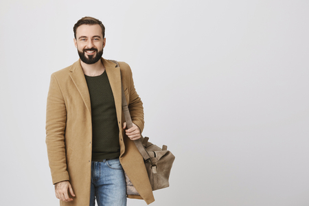 picture of handsome man smiling to the camera wearing casual clothes and a bag over white background. Businessman walks in the city centre to the restaurant to have lunch.の写真素材