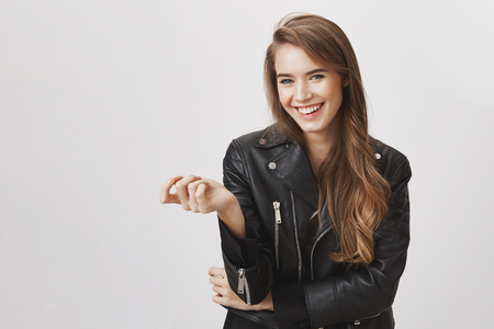 Charming woman has few points to discuss. Indoor portrait of good-looking caucasian female raising palm, counting on fingers choices and opportunities, smiling broadly, being happy over gray wallの写真素材