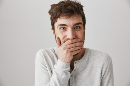 Portrait of weird crazy guy with messy haircut laughing and looking with strange expression at camera, standing over gray background, posing like psychopath. Male lost his mindの写真素材