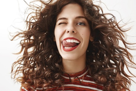Close-up shot of carefree feminine and sensual european woman with curly hair that waves in air,...