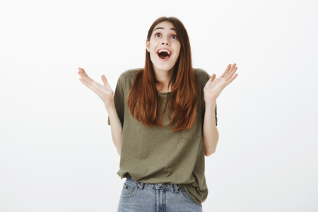 Feemale traveler happy like child seeing waterfall for first time. Shot of grinning surprised girlfriend in casual outfit, clapping and smiling broadly, looking up with amazed thrilled expressionの写真素材