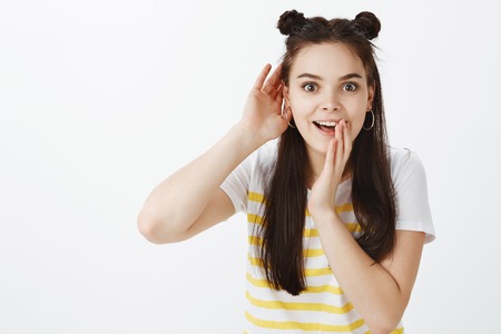 Excited joyful stylish woman with hairbuds, bending towards camera and smiling while holding palms...