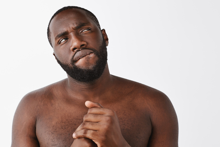 Man waking up at night wanting grab snack, thinking if it is right thing, biting lip and gazing up while making decision, clenching hands together, standing over gray background thoughtful and nakedの写真素材