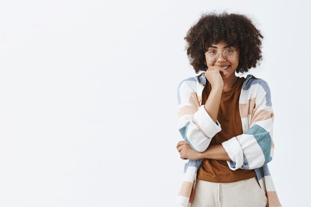 Indoor shot of silly and flirty cute dark-skinned female model with curly hairstyle in transparent...