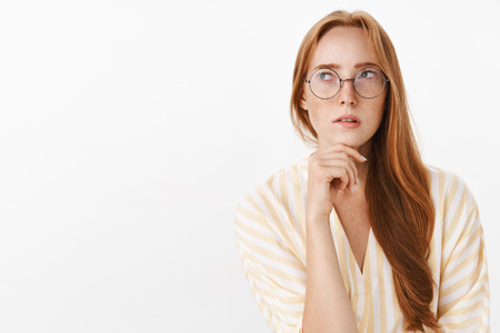 Woman remembering schedule while planning next work day standing focused and perplexed in trendy...