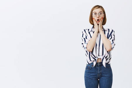 Wow, no way, cannot believe you. Attractive excited and thrilled girl with short fair hair, folding lips and gasping from surpriseの写真素材