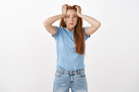 Gosh hate being student. Portrait of cute redhead woman under pressure holding hands on head with...