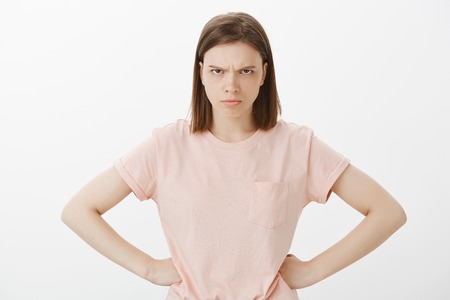 I hate you. Waist-up shot of angry and pissed off woman, holding hands on hips, looking from under...
