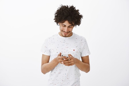 Portrait of good-looking urban man living active lifestyle, wearing trendy t-shirt, holding head...