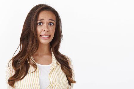 Eek she is in trouble. Embarrassed nervous cute female office manager clenching teeth making awkward concerned expression, feeling guilty, making slight mistake worried someone knowの写真素材