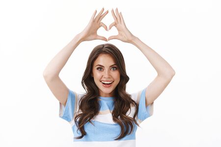 Waist-up cute tender modern glamour woman with tattoo look astonished and excited raise hands above head show heart, love gesture adore new store, confess sympathy, stand white backgroundの写真素材