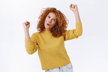 Cheerful, enthusiastic good-looking redhead woman with curly ginger hair, wear yellow sweater,...