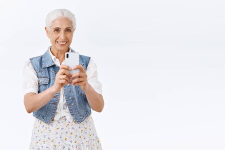 Charming modern stylish senior woman, grandmother spend time amusement park with grandkids, taking...