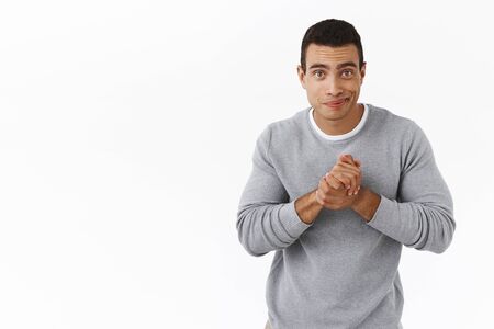 Cute handsome hispanic man relish some profit, clasp hands together in begging, asking pose, smiling...