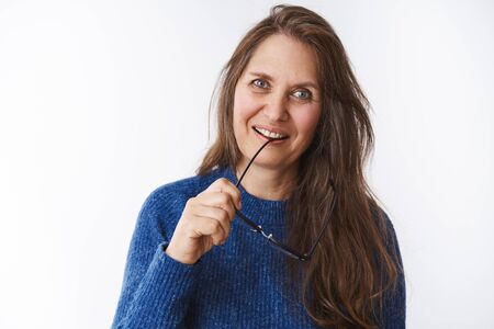 Lovely charming elderly woman with wrinkles and long hair posing flirty over white background in...