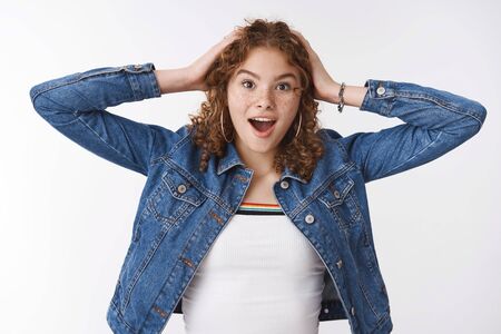Impressed surprised excited cute redhead girl cannot believe she won lottery touch head widen eyes astonished drop jaw say wow being speechless, standing white background thrilled cheeringの写真素材