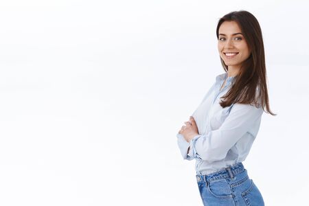 Confident successful businesswoman standing like professional, smiling satisfied, stand in profile near white copy space and turn face to came with knowing determined expression, white backgroundの写真素材