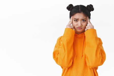 Upset and dizzy cute asian girl feel unwell, got tired or sick, massaging temples and frowning,...