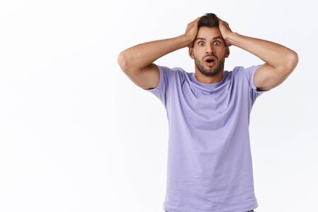 Shocked troubled and panicking young alarmed sexy guy with beard, forgot take-out chicken from fridge before wife came, grab head puzzled, gasping staring distressed and alarmed, white backgroundの写真素材