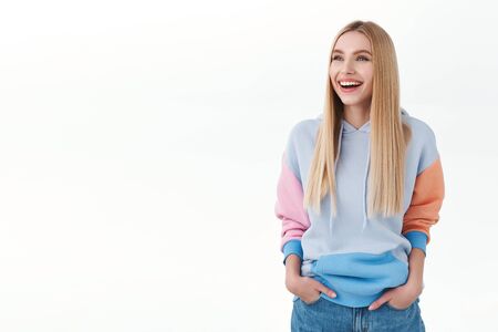 Portrait of carefree, good-looking blonde caucasian girl laughing at something hilarious, looking at...