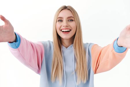 Mobile technology, people and lifestyle concept. Portrait of attractive blonde girl taking selfie on smartphone, smiling broadly, live steam, record online vlog or videocalling friendsの写真素材