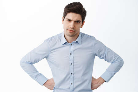 Businessman, employer scolding workers, look with displeased face, frowning upset and holding hands on waist, disappointed in someone, standing over white backgroundの写真素材