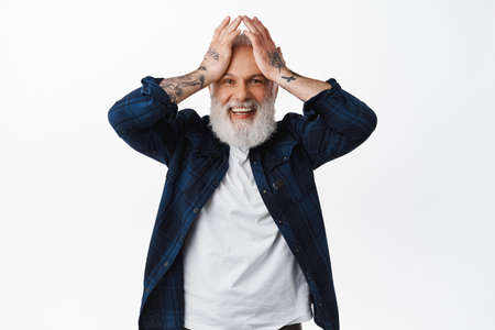 He cant believe it. Excited and surprised old man winning something, holding hands on head and...